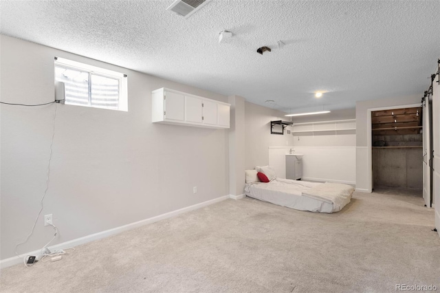 7371 Otis Ct, Arvada, CO 80003 - basement with light carpet, a textured ceiling, baseboards, and a barn door