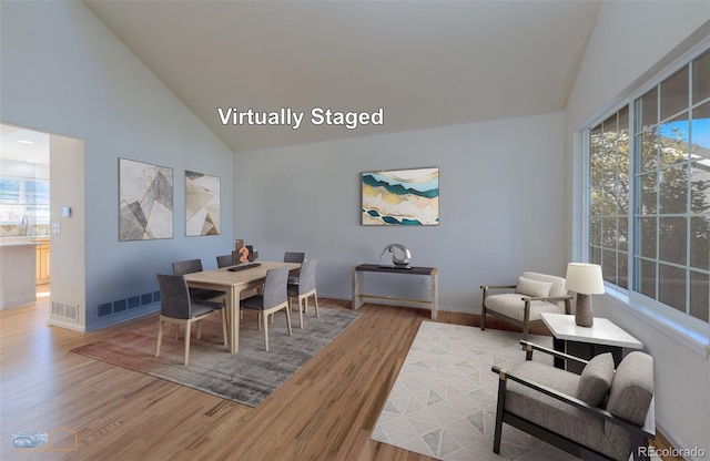 dining area with hardwood / wood-style floors, high vaulted ceiling, and sink