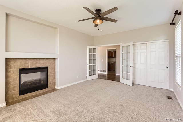 1905 Graphite Ct, Castle Rock, CO 80108 - unfurnished living room featuring french doors, carpet flooring, a ceiling fan, and a tiled fireplace