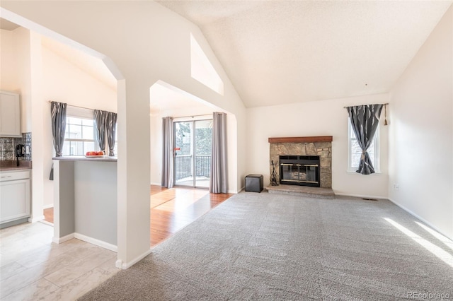 unfurnished living room featuring a fireplace, a healthy amount of sunlight, and vaulted ceiling