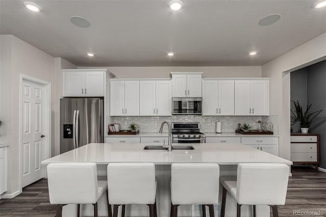 kitchen featuring a breakfast bar, sink, an island with sink, white cabinetry, and stainless steel appliances