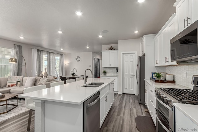 kitchen with white cabinets, appliances with stainless steel finishes, a center island with sink, and sink