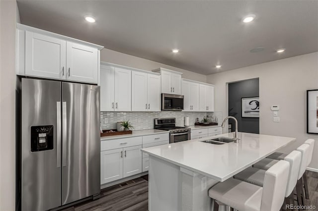 kitchen featuring sink, stainless steel appliances, a kitchen bar, a kitchen island with sink, and white cabinets