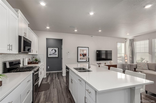 kitchen featuring sink, stainless steel appliances, an island with sink, decorative backsplash, and white cabinets