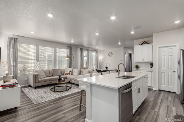 kitchen with white cabinets, appliances with stainless steel finishes, a kitchen island with sink, and sink