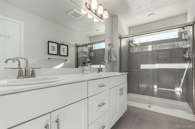 bathroom featuring a textured ceiling, vanity, tile patterned floors, and a shower with door