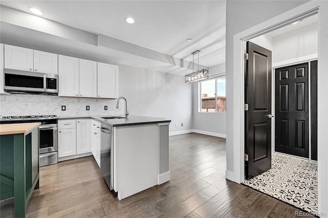 kitchen featuring appliances with stainless steel finishes, white cabinetry, sink, hanging light fixtures, and kitchen peninsula