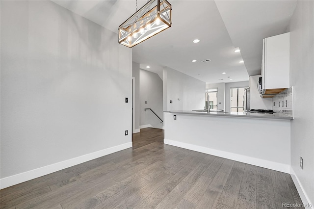 kitchen with hardwood / wood-style floors, white cabinetry, hanging light fixtures, kitchen peninsula, and stainless steel refrigerator