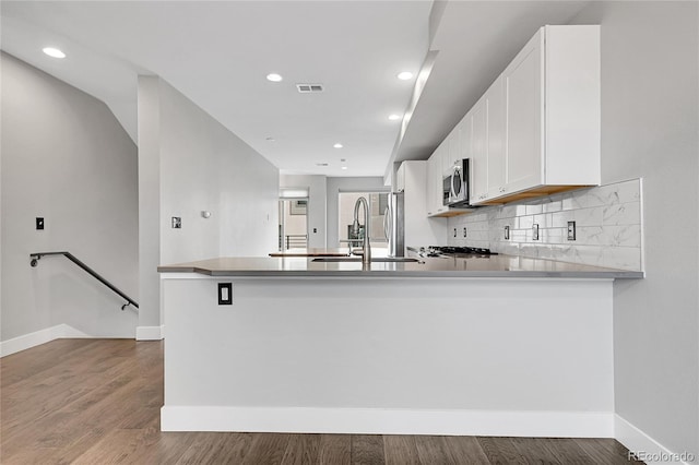 kitchen featuring hardwood / wood-style flooring, sink, white cabinetry, and kitchen peninsula