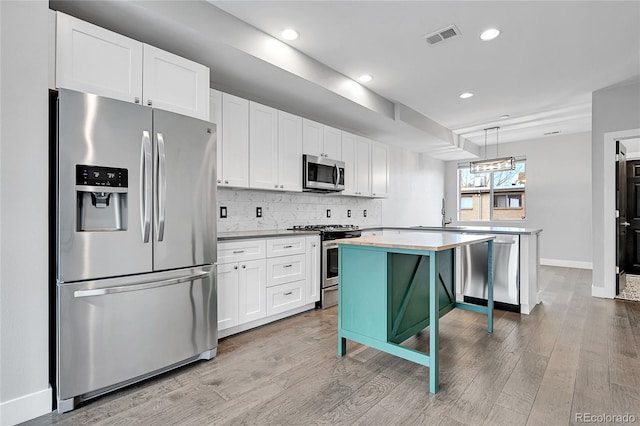 kitchen featuring white cabinets, a kitchen island, a breakfast bar area, and appliances with stainless steel finishes