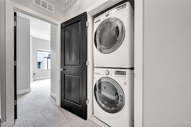 laundry area with stacked washer / dryer and light colored carpet