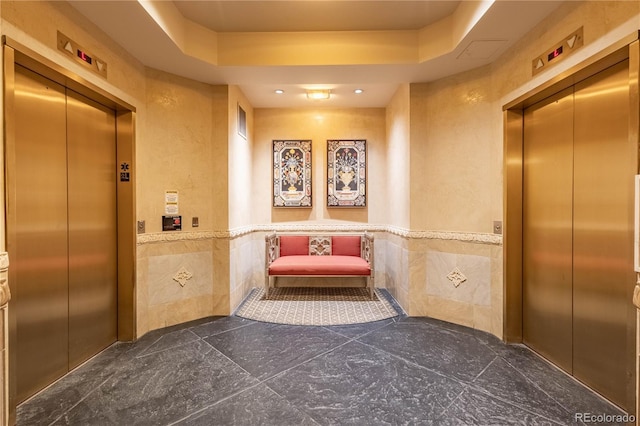 corridor with wainscoting, tile walls, and elevator