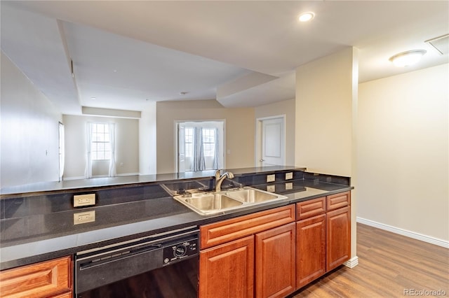 kitchen with a sink, dark countertops, dishwasher, and wood finished floors