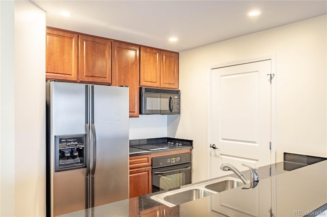 kitchen with black appliances, brown cabinetry, a sink, and recessed lighting