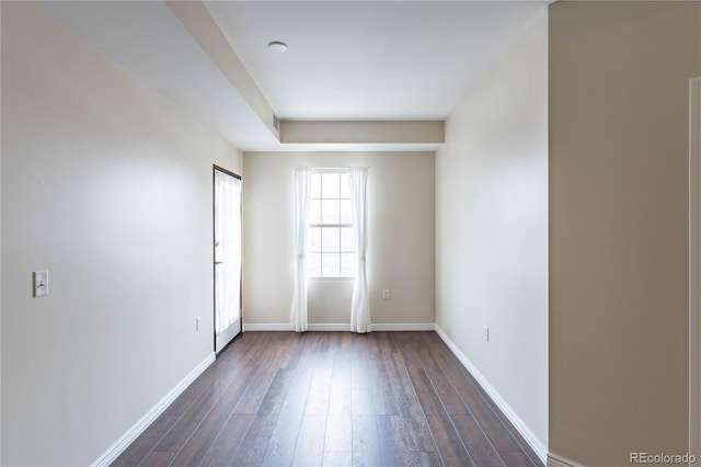 empty room with dark wood finished floors and baseboards