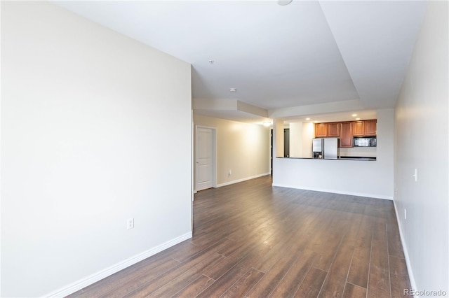 unfurnished living room featuring dark wood-type flooring and baseboards