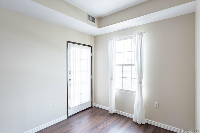 spare room with baseboards, plenty of natural light, visible vents, and dark wood-type flooring