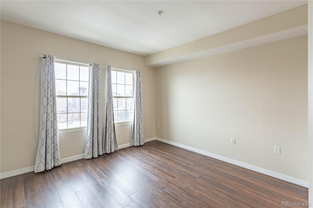 empty room with baseboards and dark wood-type flooring