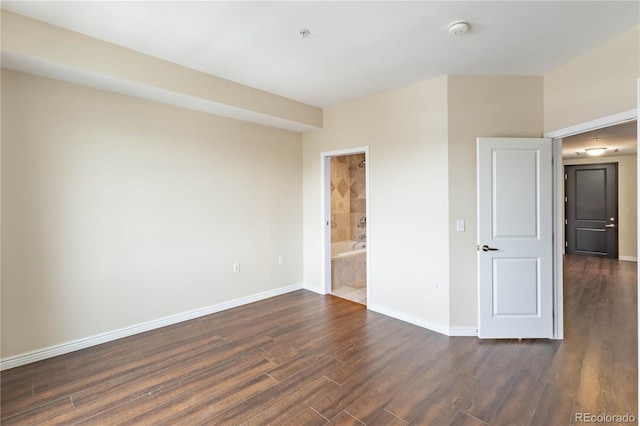 unfurnished bedroom with dark wood-style flooring, ensuite bath, and baseboards