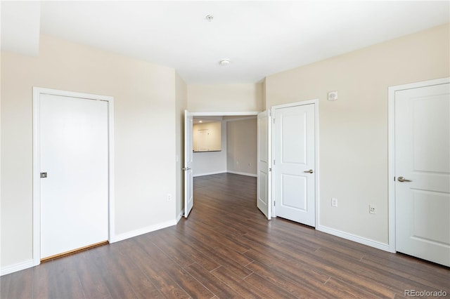 unfurnished bedroom with baseboards and dark wood-style flooring