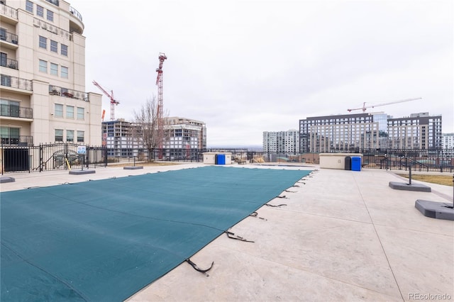 view of swimming pool with a view of city and fence