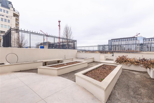 view of patio / terrace featuring a vegetable garden, fence, and a city view