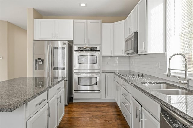 kitchen featuring white cabinets, stainless steel appliances, dark stone counters, and sink