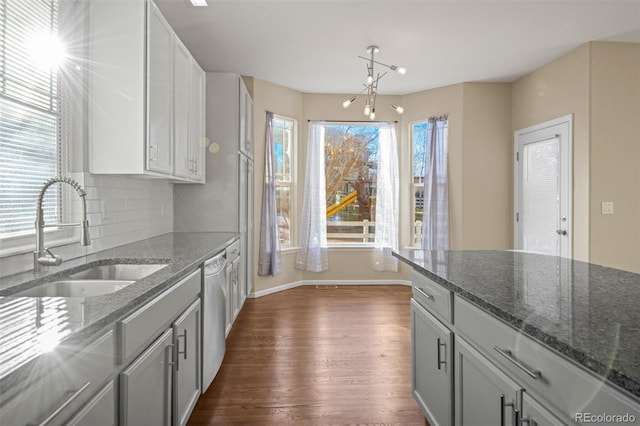 kitchen with dishwasher, dark stone counters, and sink