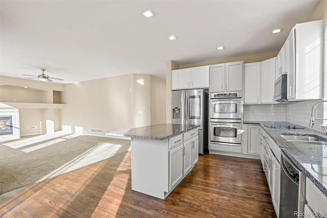 kitchen with backsplash, sink, dark stone countertops, white cabinetry, and stainless steel appliances