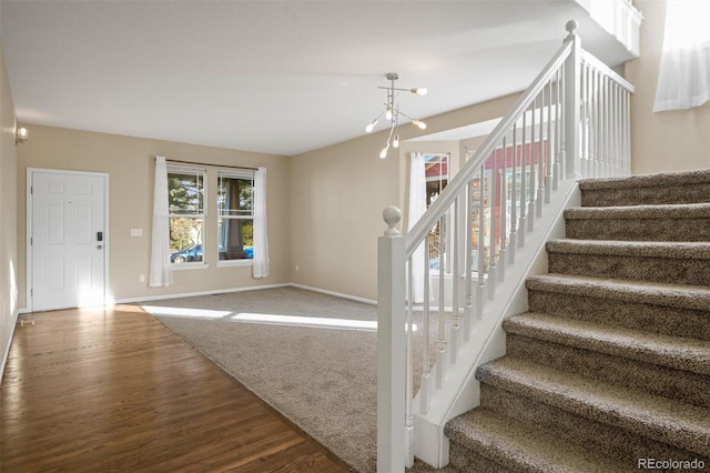 stairway featuring hardwood / wood-style floors and an inviting chandelier