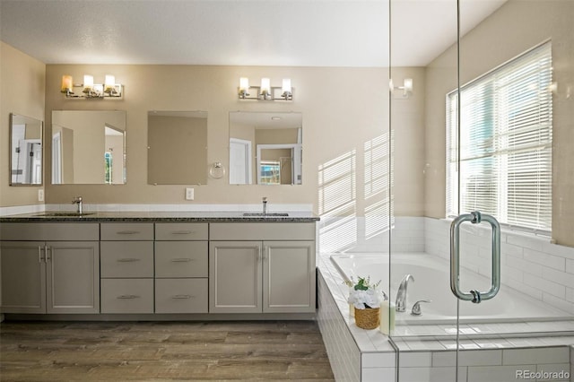 bathroom featuring vanity, a relaxing tiled tub, and hardwood / wood-style flooring