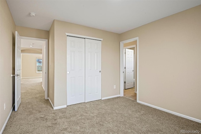 unfurnished bedroom with light carpet and a closet