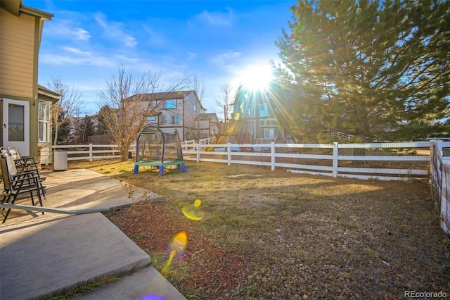 view of yard featuring a trampoline and a patio