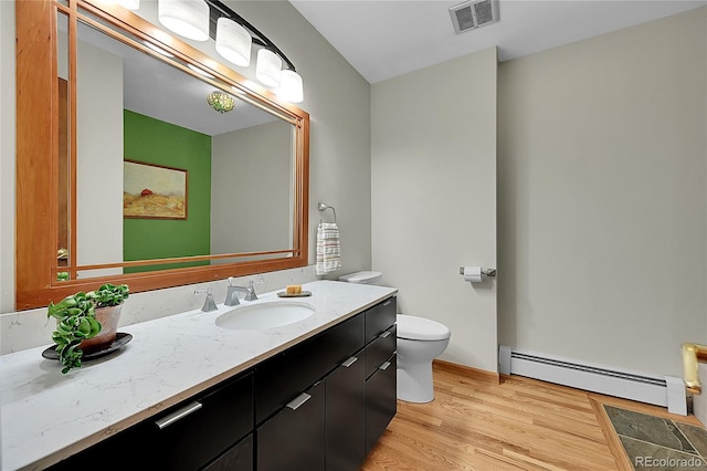 bathroom with baseboard heating, hardwood / wood-style floors, vanity, and toilet