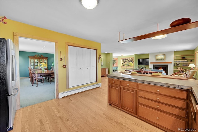 kitchen with baseboard heating, stainless steel refrigerator, and light wood-type flooring