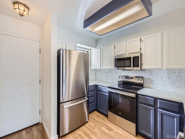 kitchen featuring stainless steel appliances, white cabinets, backsplash, and light hardwood / wood-style floors