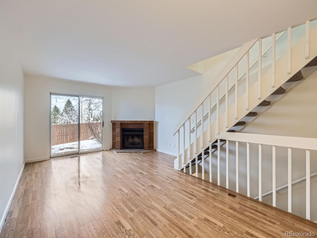 unfurnished living room featuring a brick fireplace and hardwood / wood-style floors