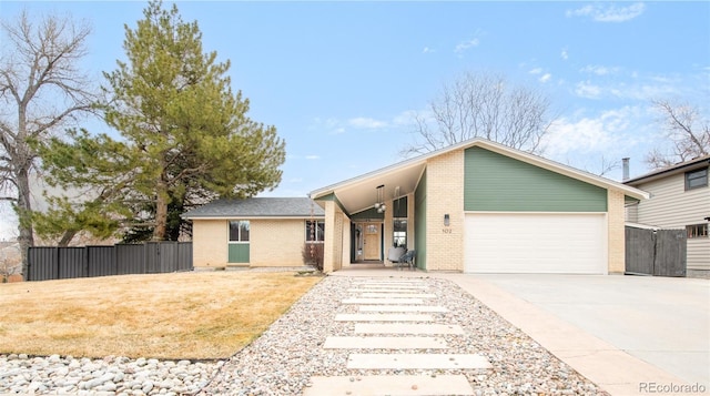 mid-century inspired home featuring an attached garage, fence, driveway, and a gate