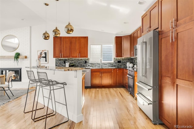 kitchen with lofted ceiling, a kitchen breakfast bar, light wood finished floors, and appliances with stainless steel finishes