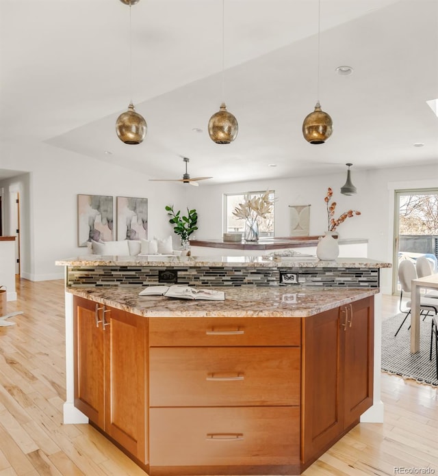 kitchen with light wood-type flooring, light stone countertops, and brown cabinetry