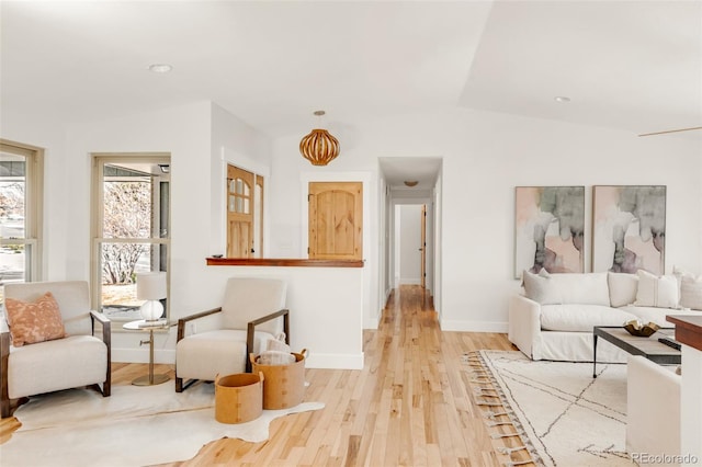 living area with vaulted ceiling, light wood-style floors, and baseboards