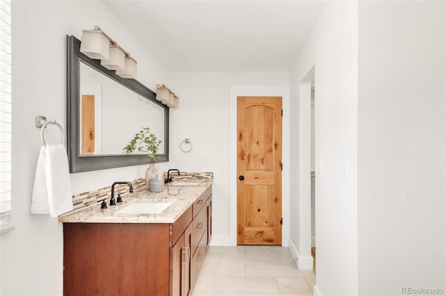 bathroom with double vanity, baseboards, tile patterned floors, and a sink