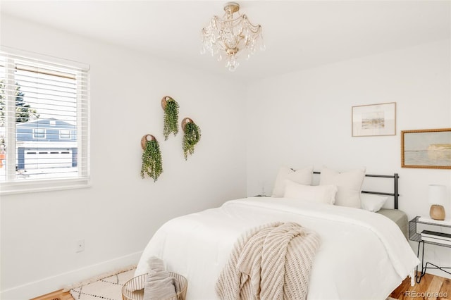 bedroom featuring an inviting chandelier, wood finished floors, and baseboards