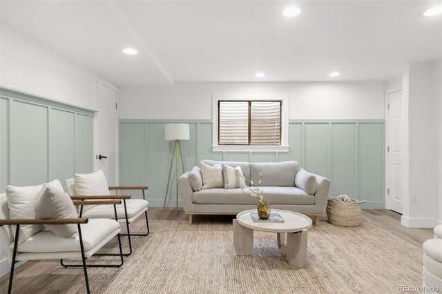 living area featuring recessed lighting, wood finished floors, wainscoting, and a decorative wall