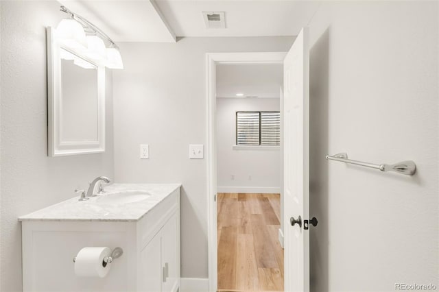 bathroom featuring visible vents, baseboards, wood finished floors, and vanity