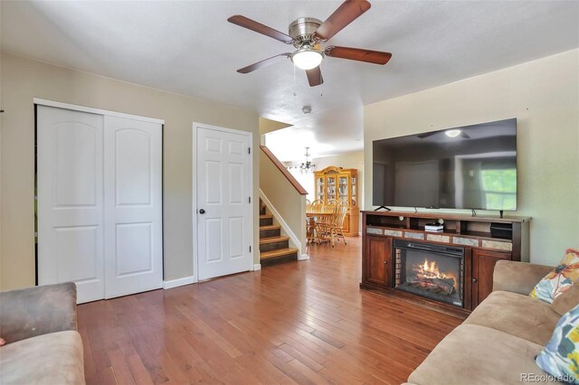 12333 Newport Ct, Brighton, CO 80602 - living area with hardwood / wood-style floors, a ceiling fan, stairway, a glass covered fireplace, and a chandelier