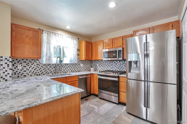 12333 Newport Ct, Brighton, CO 80602 - kitchen featuring appliances with stainless steel finishes, a sink, backsplash, light stone counters, and recessed lighting