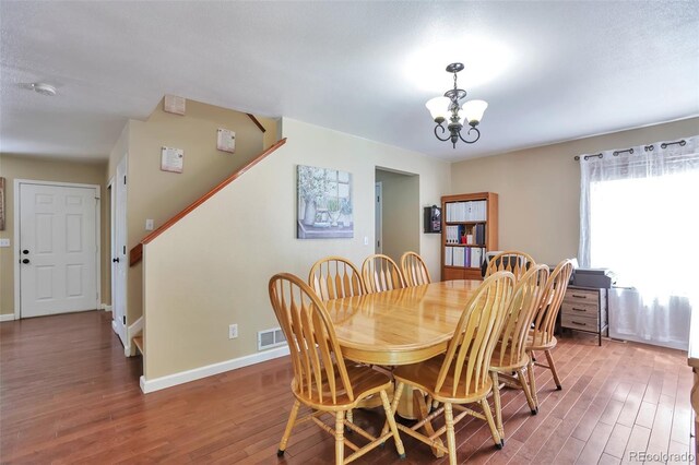 12333 Newport Ct, Brighton, CO 80602 - dining space featuring wood finished floors, a chandelier, baseboards, and stairway