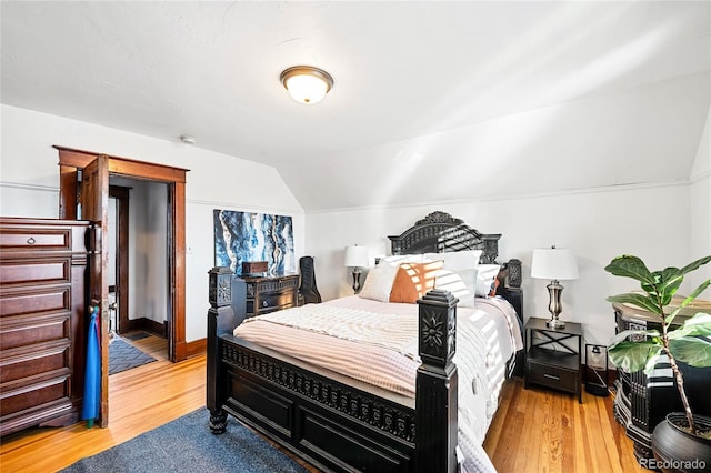 bedroom with wood-type flooring and vaulted ceiling