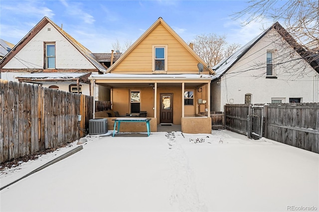 snow covered back of property featuring central AC unit and covered porch